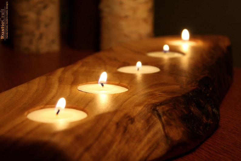 May include: A wooden candle holder with five lit tea lights. The holder is made from a natural wood slice with a rustic finish.