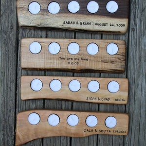 May include: Four wooden candle holders with various dates and names engraved on them. The holders are made of natural wood with a rustic finish. Each holder has four candle slots and is designed to hold tea lights.