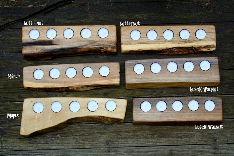 May include: Five wooden candle holders with different wood types and finishes. The holders are labeled "Butternut", "Maple", "Black Walnut". Each holder has five or six candle slots.