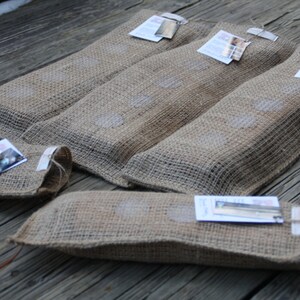 May include: Five burlap pouches with small tags attached. The pouches are filled with a product and have a rustic, natural look.