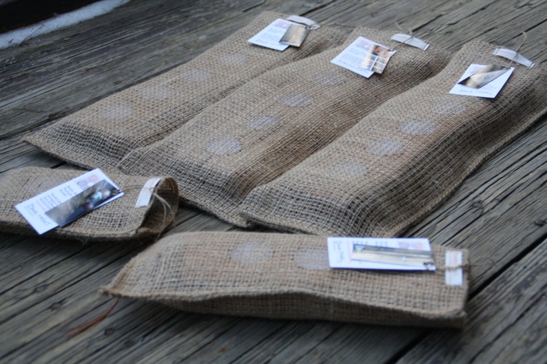 May include: Five burlap pouches with small tags attached. The pouches are filled with a product and have a rustic, natural look.