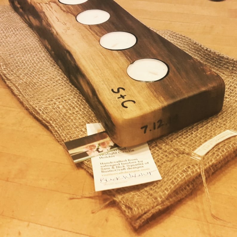 May include: A wooden candle holder with four candle wells. The holder is made from salvaged lumber and has a dark wood stain. The holder is personalized with the initials "S+C" and the date "7.12.14".