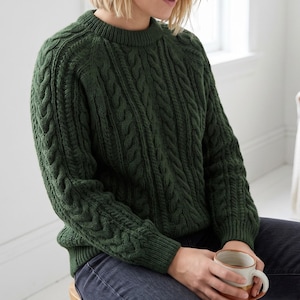 May include: A dark forest green long-sleeve sweater featuring a prominent vertical cable knit pattern throughout the front and sleeves. The garment has a ribbed crew neckline, ribbed cuffs, and a ribbed hem, providing a structured fit.