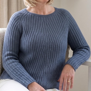 May include: A slate blue long-sleeve sweater featuring a vertical ribbed knit pattern throughout the body and sleeves, with a rounded neckline and raglan-style shoulder seams that create a textured, fitted appearance across the chest and arms.