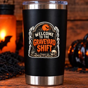 May include: A matte black stainless steel tumbler with a clear lid and a silver base. The front features a graphic of a tombstone with a full moon, a bat, and a skull, with the text "WELCOME TO THE GRAVEYARD SHIFT" in white and orange.
