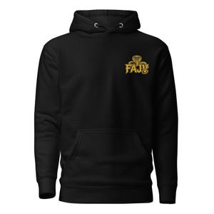 May include: A black hooded sweatshirt featuring a front kangaroo pocket and long sleeves. On the upper left chest, there is a gold-colored graphic design depicting a cobra snake coiled above the bold, capitalized text FAJV in a stylized font.