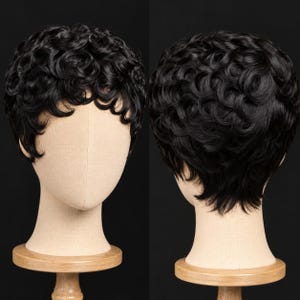 Puede incluir: Una peluca corta de color negro con rizos apretados y definidos en un corte pixie. El cabello tiene un acabado brillante y se muestra en una cabeza de maniquí beige, exhibiendo la vista frontal con flequillo y la vista trasera con capas.