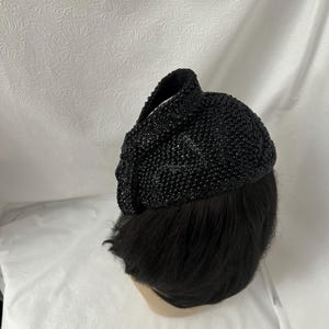 May include: A black beaded hat with a rounded shape. The hat is made of small, black beads that are sewn together.