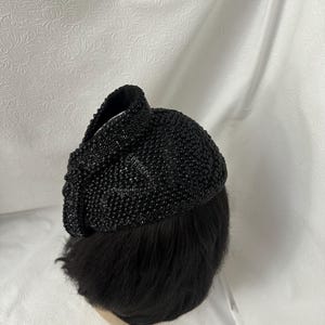 May include: A black beaded hat with a rounded shape. The hat is made of small, black beads that are sewn together.