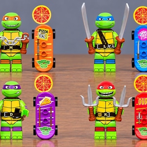 May include: Four green turtle action figures with masks in orange, blue, purple, and red. Each figure holds a signature weapon and stands next to a matching coloured skateboard featuring a pizza graphic and the text Pizza Time or Dude.