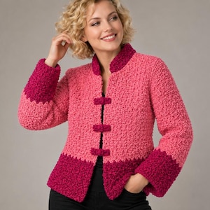 Puede incluir: Una chaqueta de punto texturizado con un diseño de bloques de color en tonos rosa claro y magenta oscuro. La chaqueta presenta un cuello alzado, mangas largas con puños en magenta oscuro y tres cierres de palanca en la parte delantera.