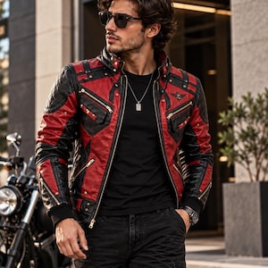 Puede incluir: Una chaqueta de cuero roja y negra con cuello alto, paneles acolchados en los hombros, múltiples bolsillos con cremallera y herrajes dorados. La chaqueta se lleva sobre una camiseta negra lisa, combinada con pantalones cargo negros y un collar.