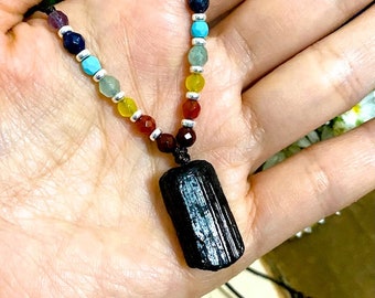 Puede incluir: Un collar con un colgante de turmalina negra, un cordón negro y siete cuentas de chakra en colores arcoíris. Las cuentas son de amatista, lapislázuli, turquesa, aventurina verde, citrino amarillo, cornalina y jaspe rojo.