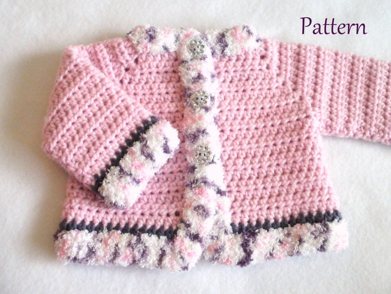 May include: Pink crocheted baby cardigan with a white and purple trim. The cardigan has a button closure and is made with a soft yarn.