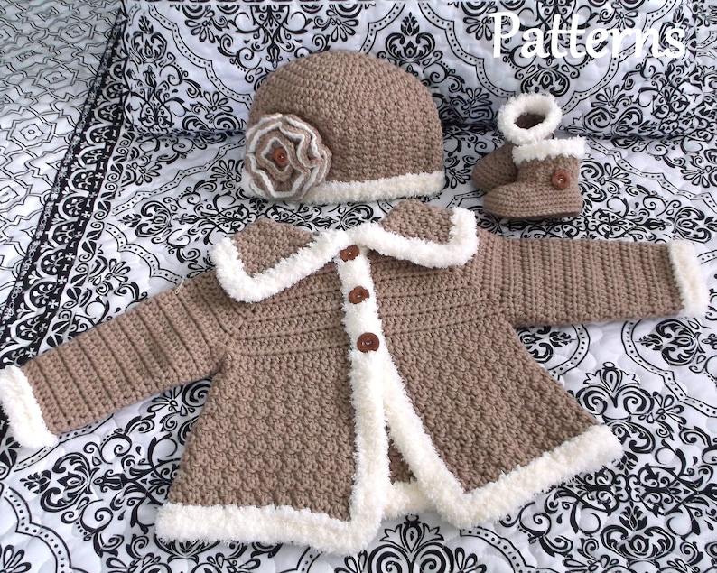 K&ouml;nnte beinhalten: Eine braune geh&auml;kelte Babyjacke mit wei&szlig;em Pelzbesatz, eine passende braune geh&auml;kelte M&uuml;tze mit wei&szlig;em Pelzbesatz und einer braunen Bl&uuml;te sowie ein Paar braune geh&auml;kelte Booties mit wei&szlig;em Pelzbesatz.