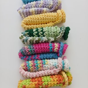 Puede incluir: Una pila de estropajos de ganchillo de colores en varios patrones, incluyendo verde, rosa, amarillo y azul.