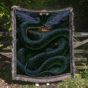 May include: A woven throw blanket featuring a large, coiled dark green snake with glowing red eyes and an open mouth. The background depicts a dark, stormy landscape with a fiery horizon. The border has a repeating pattern of ancient symbols.