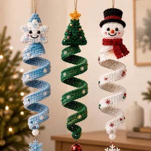 Könnte beinhalten: Drei hängende Häkelornamente bestehend aus einer hellblauen Schneeflocke, einem grünen Weihnachtsbaum und einem weißen Schneemann. Jedes Ornament hat einen spiralförmigen Körper mit kleinen Verzierungen und einem Anhänger.