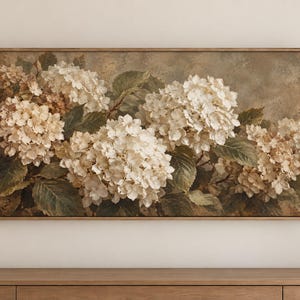 Op de afbeelding: Een rechthoekig wandkunstwerk met een horizontaal schilderij van trossen witte en crèmekleurige hortensiabloemen met donkergroene bladeren, tegen een gedempte, getextureerde bruine achtergrond en gevat in een dunne houten lijst.