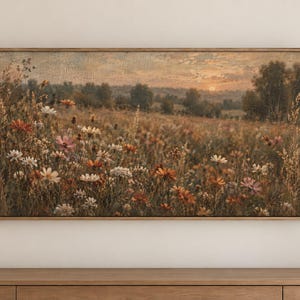 May include: A rectangular landscape painting in a wooden frame depicting a field of wildflowers in shades of white, pink, and orange under a sunset sky. The scene features tall grasses and distant trees, rendered with a textured, painterly finish.