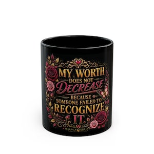 May include: A black ceramic mug featuring a floral design with red roses and a butterfly. The text reads: MY WORTH DOES NOT DECREASE BECAUSE SOMEONE FAILED TO RECOGNIZE IT. The design includes gold and pink lettering and the name MARIA VALENTINE.