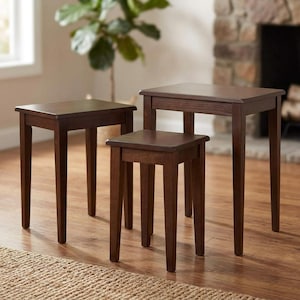 May include: A set of three dark brown wooden nesting tables with rectangular tops and four straight legs each. The tables are arranged in a tiered formation, showing varying heights and sizes, with a smooth finish on the wood surfaces.