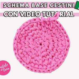 Può includere: Un cerchio di uncinetto rosa, una base per un cestino, con il testo "SCHEMA BASE CESTINI CON VIDEO TUTORIAL" sopra.