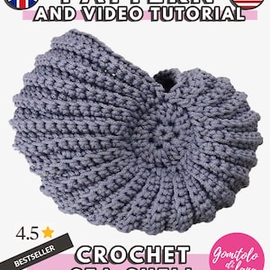 Könnte beinhalten: Eine graue gehäkelte Muschel mit Spiralstruktur. Das Bild enthält den Text PATTERN AND VIDEO TUTORIAL, 4.5 BESTSELLER, CROCHET SEA SHELL und Gomitolo di lana sowie Symbole der britischen und amerikanischen Flagge in den Ecken.