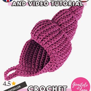 Op de afbeelding: Een donkerroze gehaakte zeeschelp met een spiraalvorm en een klein lusje aan de basis. De afbeelding bevat de tekst PATTERN AND VIDEO TUTORIAL, 4.5 BESTSELLER, CROCHET SEA SHELL en Gomitolo di lana, samen met iconen van vlaggen.