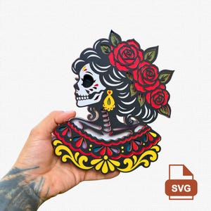 May include: A multi-layered wooden wall art piece depicting a stylized skull figure in profile. The design features black hair adorned with three red roses and green leaves, a yellow earring, and a decorative collar in red, black, and yellow.