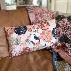 Finished Honeycomb Pillows made with Enchanted fabric collections by Cloud9 Fabrics, displayed on a brown leather couch with a Trip Around The World Quilt. The quilted pillows feature a honeycomb-inspired patchwork design and are sewn in a 12" x 20" lumbar size.