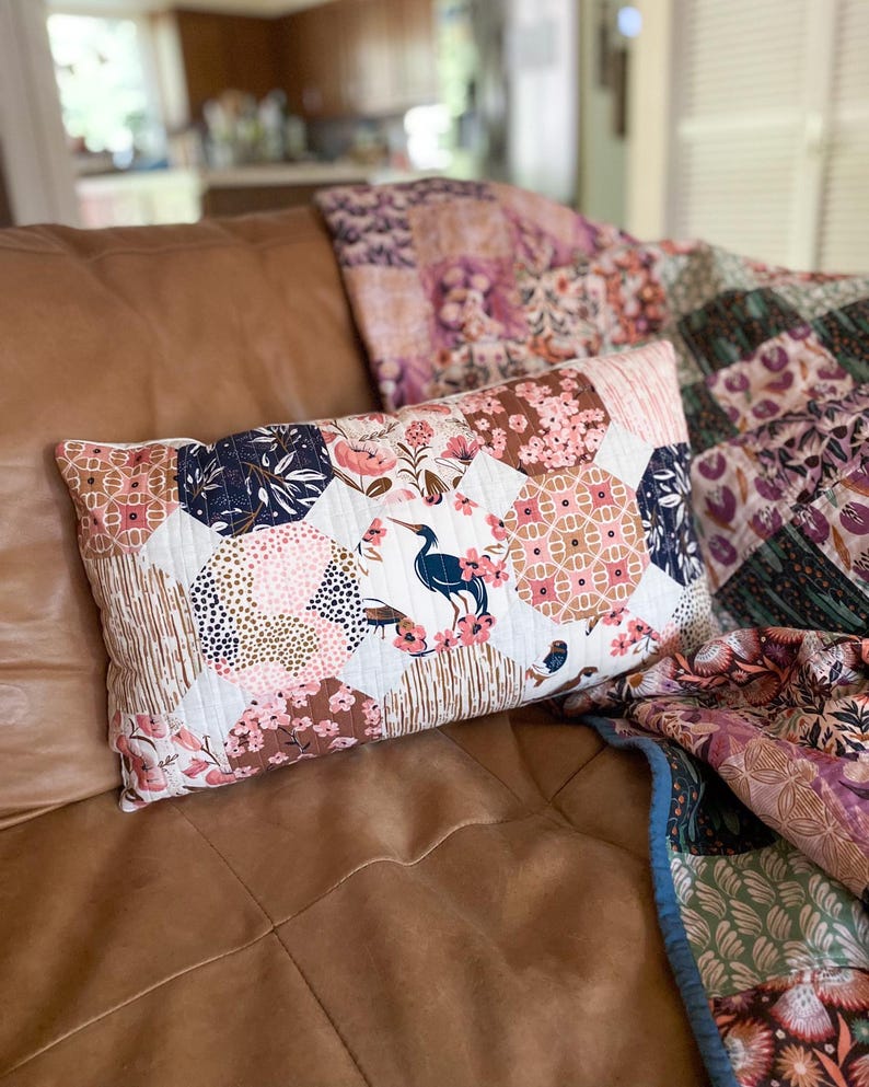 Finished Honeycomb Pillows made with Enchanted fabric collections by Cloud9 Fabrics, displayed on a brown leather couch with a Trip Around The World Quilt. The quilted pillows feature a honeycomb-inspired patchwork design and are sewn in a 12" x 20" lumbar size.