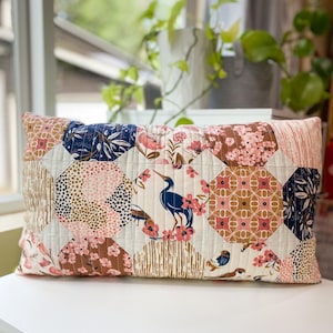 Honeycomb Pillow front view made with Enchanted fabric, displayed on a white table in front of a window. Features a modern hexagon-inspired patchwork design.