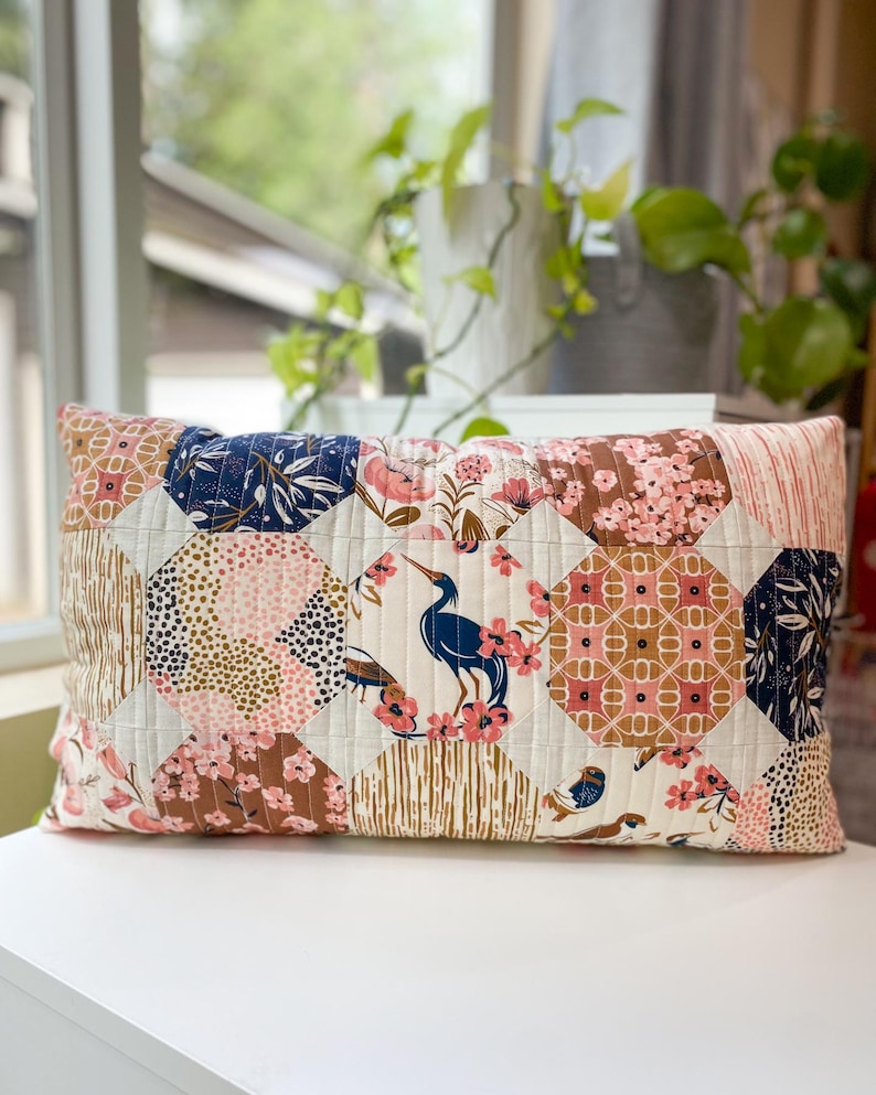 Honeycomb Pillow front view made with Enchanted fabric, displayed on a white table in front of a window. Features a modern hexagon-inspired patchwork design.