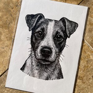 Può includere: Un'illustrazione a inchiostro bianco e nero della testa di un cane Jack Russell Terrier su un foglio di carta rettangolare bianco. Il disegno utilizza tecniche dettagliate di puntinismo e tratteggio per creare texture e ombre sul muso.