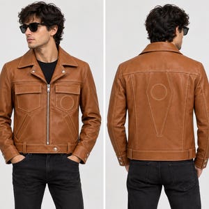May include: A tan leather jacket featuring a front zipper closure, a pointed collar, two chest pockets with flaps, and long sleeves with buttoned cuffs. The back displays a large geometric stitched design with a central circle and triangular panel.