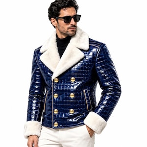 Puede incluir: Una chaqueta de doble botonadura en un acabado azul profundo brillante con un patr&oacute;n texturizado de piel de cocodrilo. La prenda presenta un cuello ancho de piel sint&eacute;tica blanca y pu&ntilde;os a juego, acentuados por seis grandes botones dorados.