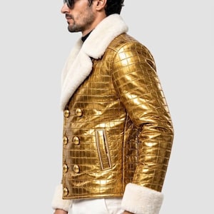 Puede incluir: Una chaqueta de doble botonadura con acabado en oro met&aacute;lico y un patr&oacute;n texturizado de piel de cocodrilo. La chaqueta presenta un cuello ancho de piel sint&eacute;tica blanca y pu&ntilde;os a juego de piel sint&eacute;tica blanca, con seis botones dorados.