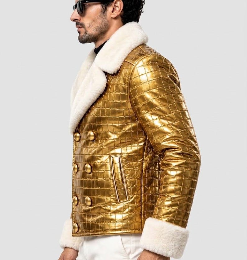 Puede incluir: Una chaqueta de doble botonadura con acabado en oro met&aacute;lico y un patr&oacute;n texturizado de piel de cocodrilo. La chaqueta presenta un cuello ancho de piel sint&eacute;tica blanca y pu&ntilde;os a juego de piel sint&eacute;tica blanca, con seis botones dorados.