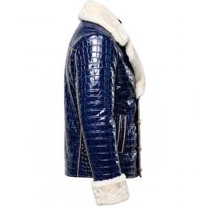 Puede incluir: Una chaqueta azul marino brillante con un patr&oacute;n texturizado de piel de cocodrilo, que presenta un cuello grueso de piel sint&eacute;tica blanca y pu&ntilde;os a juego. La chaqueta incluye botones dorados en el cierre frontal y detalles de ribete beige.