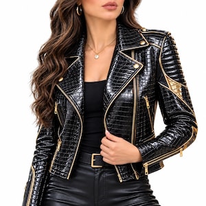 May include: A black jacket with a glossy crocodile-embossed texture, featuring gold-toned metal zips, snap buttons, and metallic gold piping accents along the lapels, shoulders, and sleeves. The jacket has a structured collar and long sleeves.