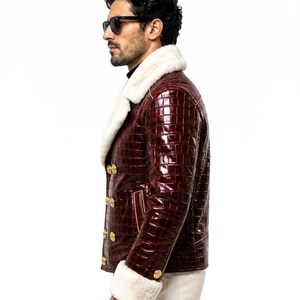 Puede incluir: Una chaqueta de doble botonadura en color burdeos intenso con una textura brillante en relieve de piel de cocodrilo. La chaqueta presenta un cuello ancho de piel sint&eacute;tica blanca y pu&ntilde;os de piel sint&eacute;tica a juego, con botones dorados.