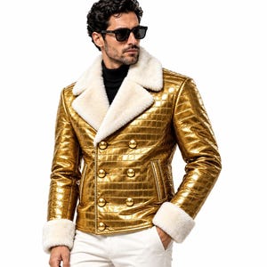 Puede incluir: Una chaqueta de doble botonadura con acabado dorado met&aacute;lico y un patr&oacute;n de cuadr&iacute;cula texturizado. La prenda presenta un cuello ancho de piel sint&eacute;tica blanca y pu&ntilde;os a juego de piel sint&eacute;tica blanca. Se cierra con seis botones dorados grandes y redondos.