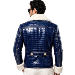 Puede incluir: Una chaqueta azul marino brillante con un patr&oacute;n texturizado de piel de cocodrilo, con cuello y pu&ntilde;os de piel sint&eacute;tica blanca. La chaqueta incluye una tira horizontal en la espalda con dos botones dorados y ribetes dorados en las costuras.