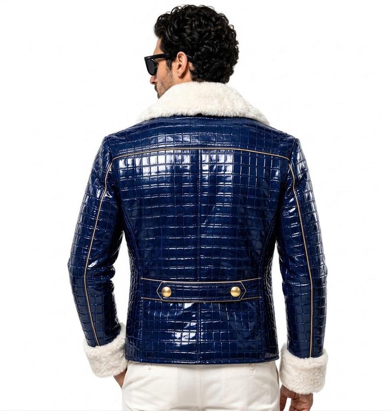 Puede incluir: Una chaqueta azul marino brillante con un patr&oacute;n texturizado de piel de cocodrilo, con cuello y pu&ntilde;os de piel sint&eacute;tica blanca. La chaqueta incluye una tira horizontal en la espalda con dos botones dorados y ribetes dorados en las costuras.