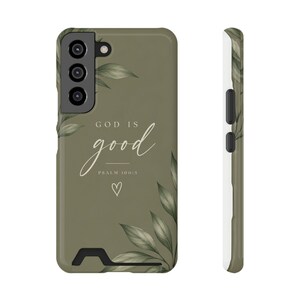May include: An olive green smartphone case featuring a botanical leaf design in the corners. The text reads "GOD IS good" followed by "PSALM 100:5" and a small hand-drawn heart outline. The case includes cutouts for the camera and side buttons.