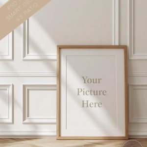 May include: A vertical wooden picture frame with a light-colored mat board, featuring the text "Your Picture Here" in the center. The frame is positioned against a white paneled wall with soft shadows cast across the surface and the wooden floor.