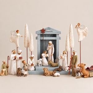 May include: A nativity scene set featuring stylized resin figurines of figures, animals, and two angels on metal rods. The central structure is a blue wooden stable with a red star. The collection includes sheep, a camel, and tall white trees.
