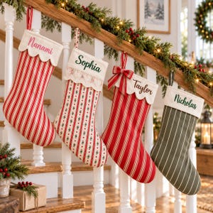 May include: Four hanging Christmas stockings with personalised names. The first is red and white striped with Nanami, the second is floral with Sophia, the third is red and white striped with Taylor and a bow, and the fourth is olive green with Nicholas.