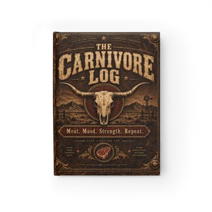 May include: A dark brown hardcover journal titled The Carnivore Log, featuring a central steer skull illustration, a desert landscape, and the text Meat. Mood. Strength. Repeat. The cover includes decorative gold-toned accents and stars.
